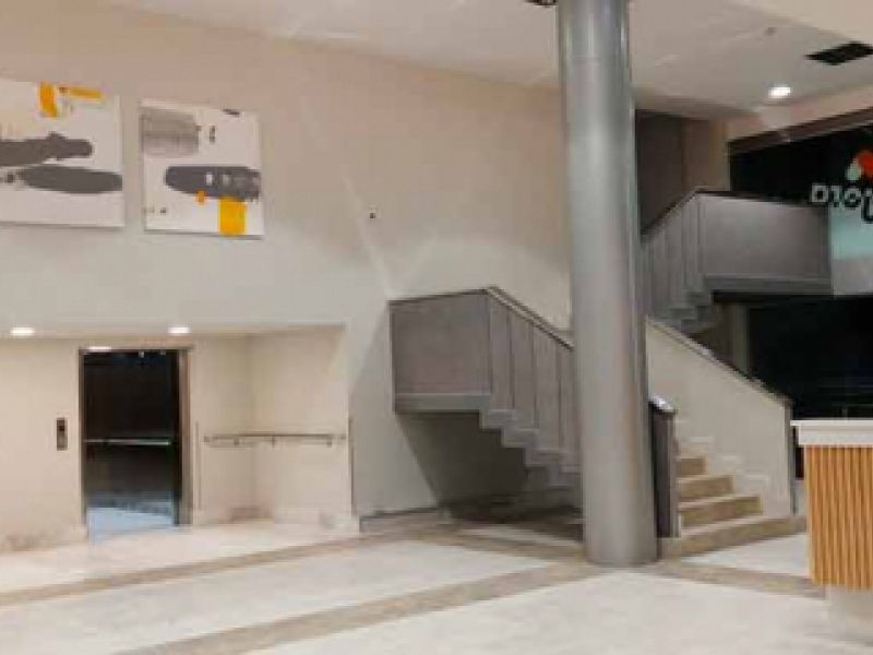 Interior de dos pisos con acceso a ascensores y escalera